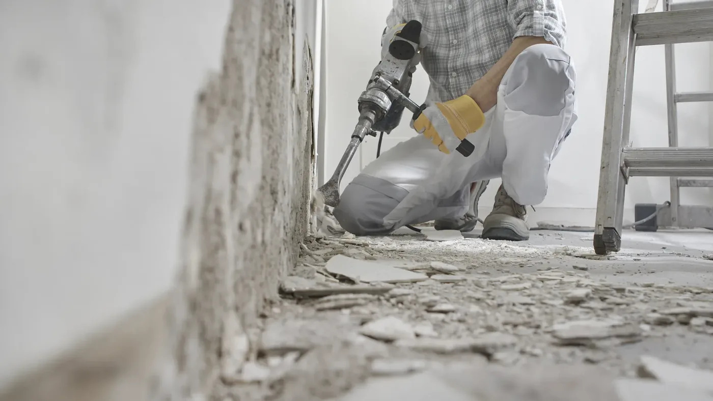Handwerker entfernt bei einer Renovierung alten Putz mit dem Meißelhammer