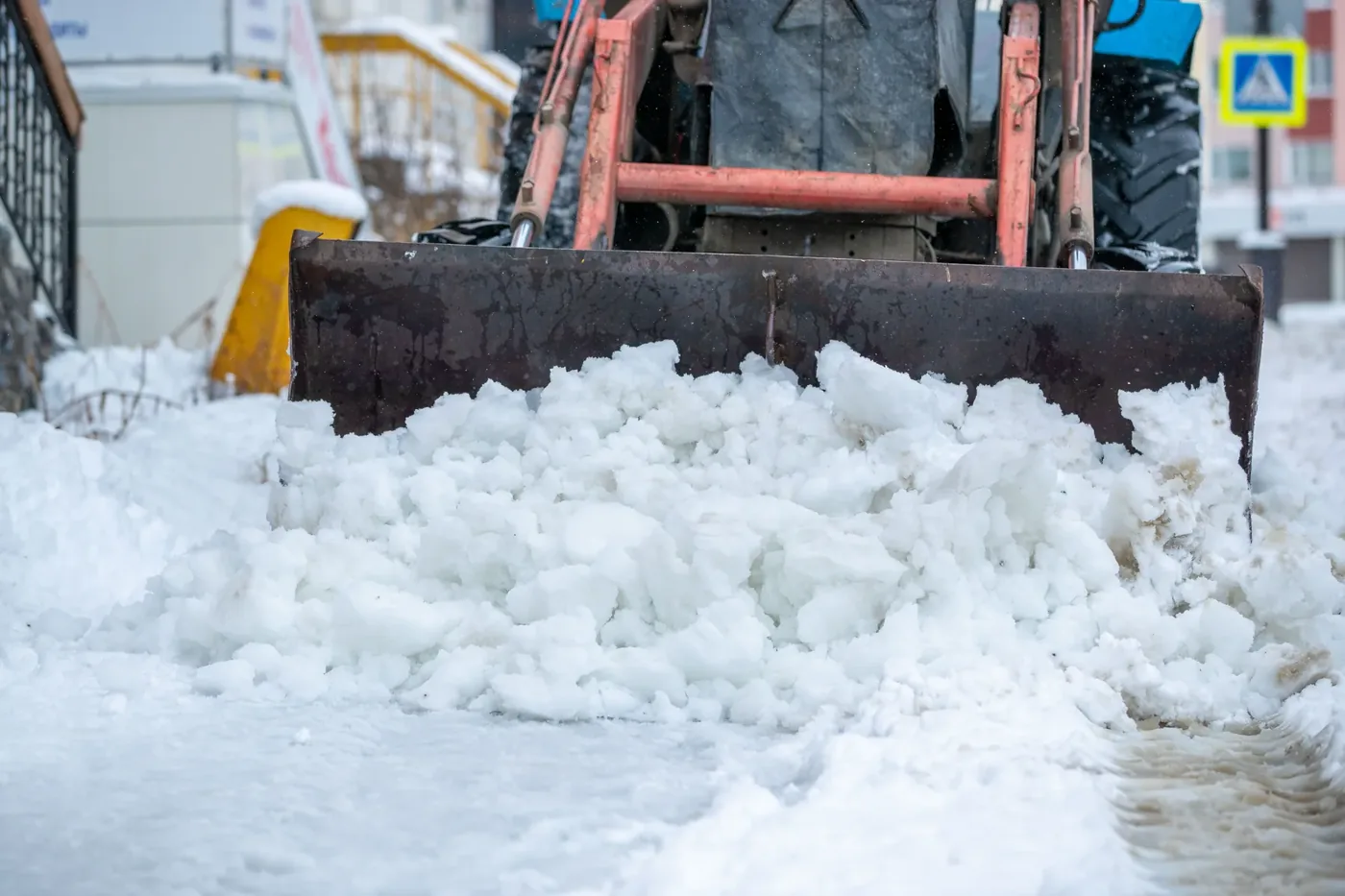 Räumschild schiebt Schnee von einem Gehweg im Winterdienst